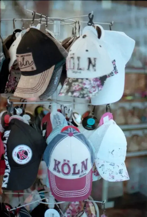 Display of various stylish hats including baseball caps on a rack with KÖLN designs.